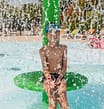 Les Mouettes campsite - The water park - Child playing under a water jet in the Aqua garden