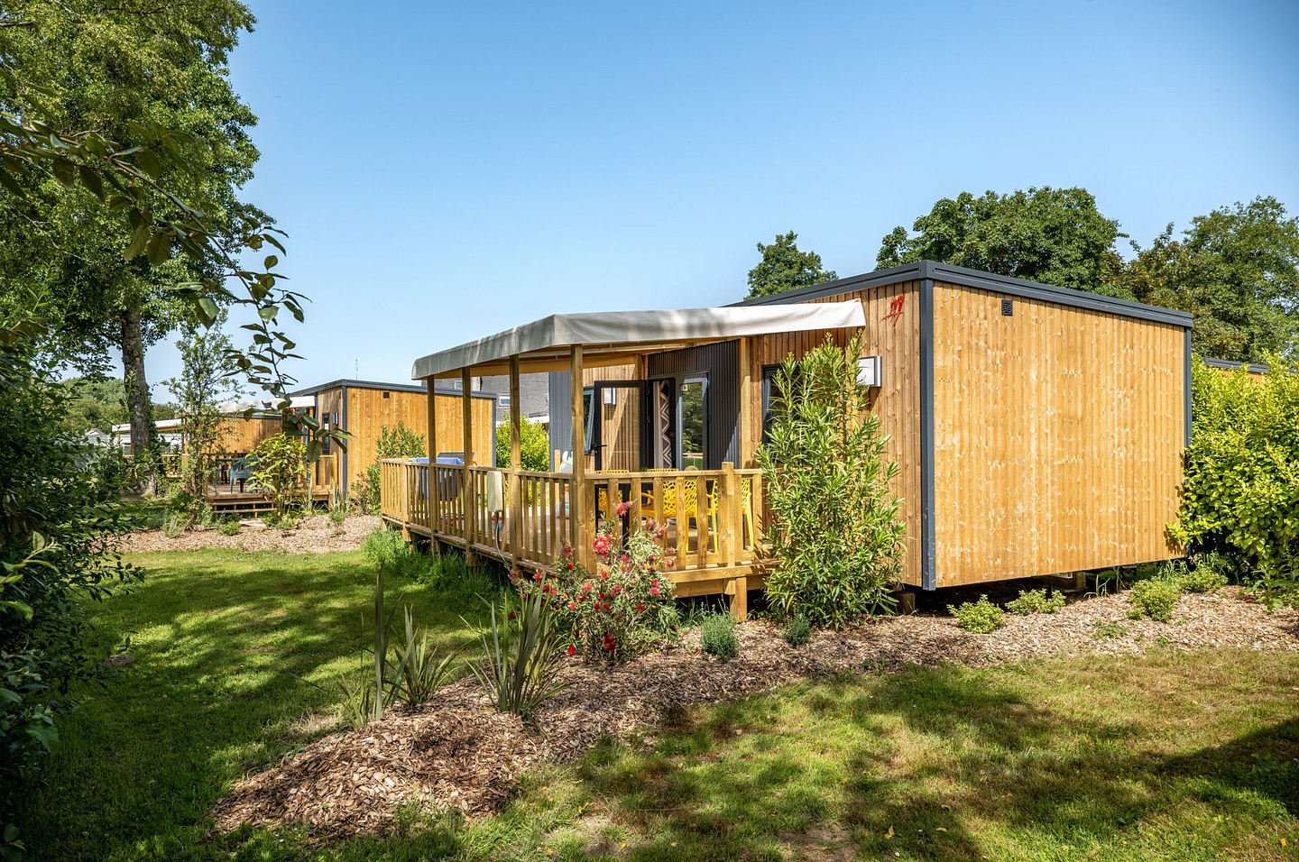 Vue sur le village des Cottages Confort Premium avec bardage bois et terrasses semi-couvertes au camping Domaine de Mesqueau.