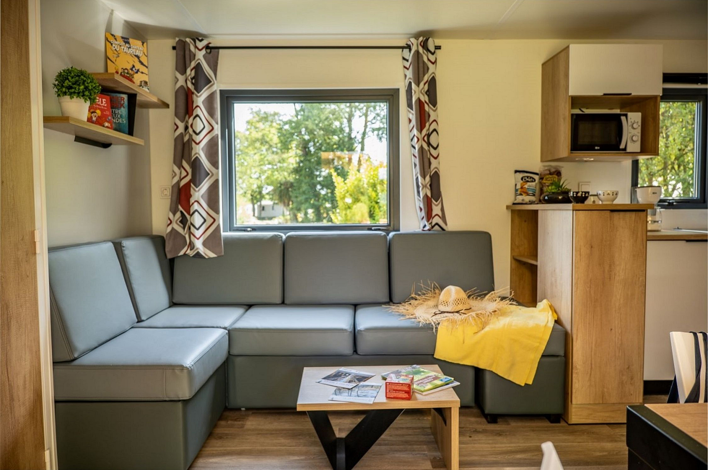 Salon avec cuisine et TV dans un cottage Confort Premium 3 chambres au camping Domaine de Mesqueau.