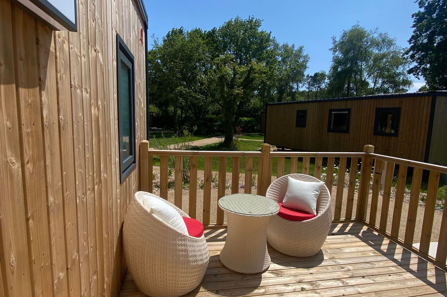 Terrasse ensoleill&eacute;e d&rsquo;un Lodge Premium avec mobilier en rotin au Domaine de Mesqueau.