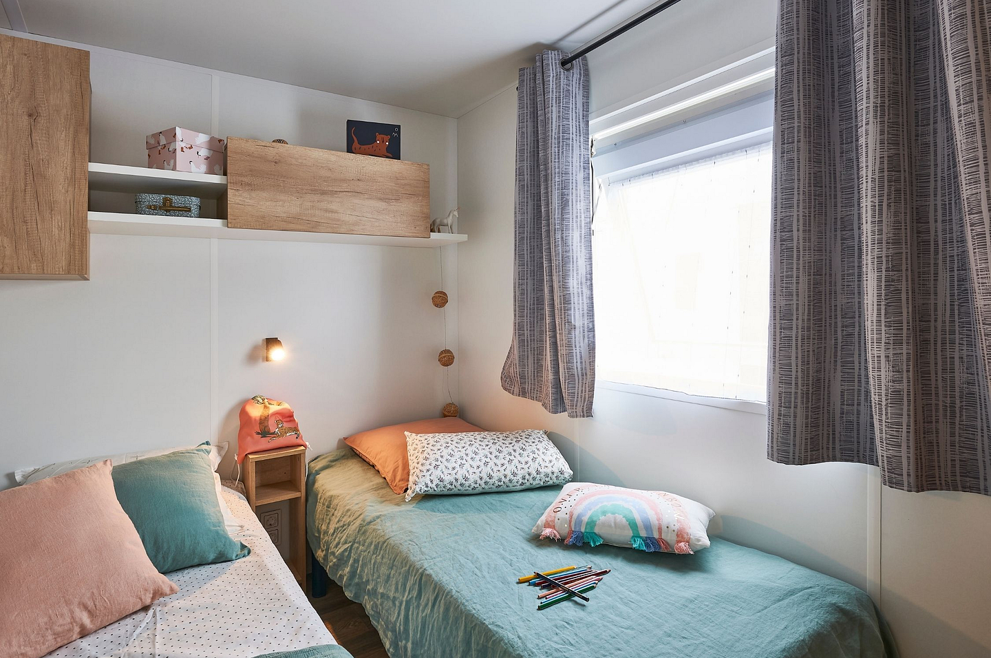 Chambre avec deux lits simples, d&eacute;cor&eacute;e avec des couleurs pastel et des &eacute;l&eacute;ments ludiques, au Lodge Serenity du camping Domaine de Mesqueau.