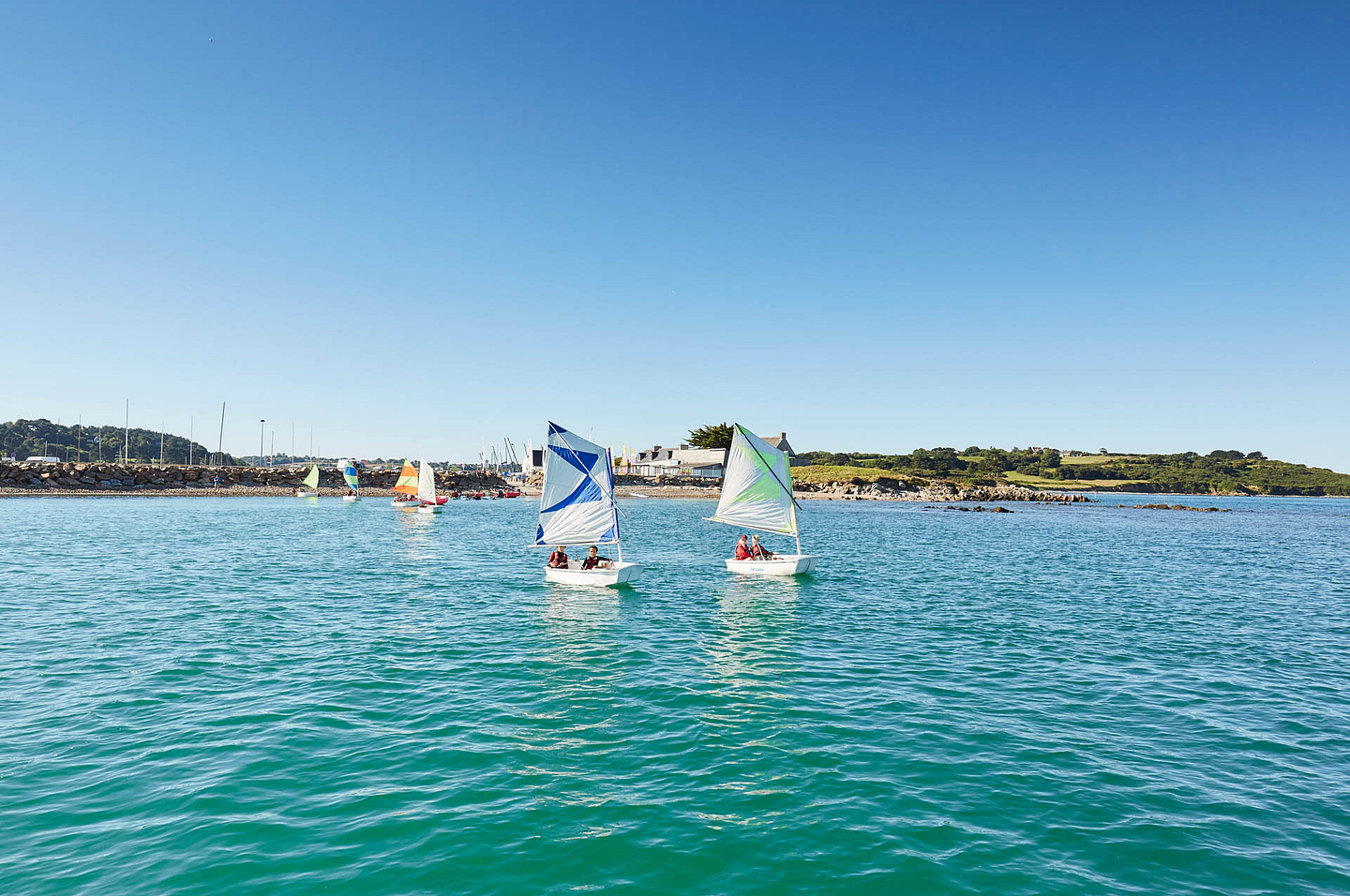 Petits voiliers color&eacute;s naviguant dans les eaux calmes au large du port de Terenez, pr&egrave;s de Plougasnou, en Bretagne.
