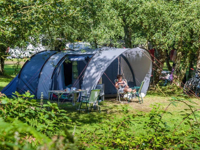Tente familiale moderne install&eacute;e &agrave; l&rsquo;ombre au camping Mesqueau avec vacanci&egrave;re d&eacute;tendue sur chaise longue