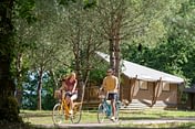 Camping Les Couleurs de la Coubre - Activités et animations - Couple qui fait du vélo devant les tentes glamping