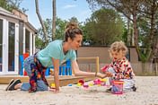 Camping Les Couleurs de la Coubre - Activités et animations - Enfant qui fait un château de sable au club enfant sous la supervision d\'une animatrice