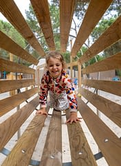 Camping Les Couleurs de la Coubre - Activités et animations - Enfant dans un tunnel en bois de l\'aire de jeux