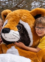 Camping Les Couleurs de la Coubre - Activités et animations - Enfants dans les bras de la mascotte en peluche