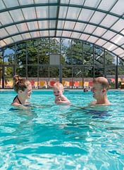 Camping Parc du Val de Loire - Couple avec son bébé qui se baigne dans la piscine couverte