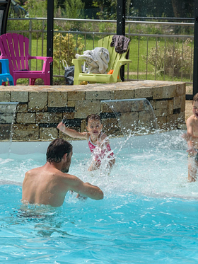 Famille profitant de la pataugeoire ludique et chauffée du Domaine de Mesqueau, avec des jeux d’eau pour les enfants dans un cadre convivial.