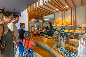 Camping Les Mouettes - Services - Famille qui achète une baguette de pain à la boulangerie