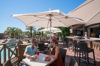 Camping Le Brasilia, restauration, couple mangeant une pizza à la terrasse du snack bar au bord de la piscine