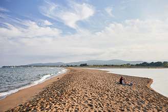 Pärchen, das auf dem Strand Les Esclamandes sitzt - Campingplatz Fréjus Ecolodge L‘Etoile d\'Argens