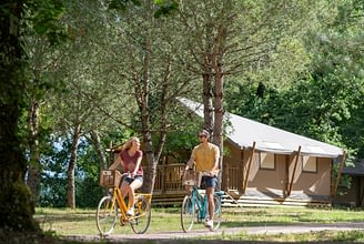 Camping Les Couleurs de la Coubre - Activités et animations - Couple qui fait du vélo devant les tentes glamping