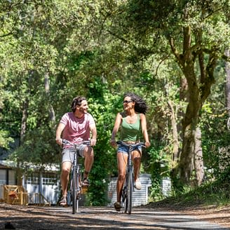 Camping Le Logis - Activités et animations - Couple qui se balade en vélo dans les allées du camping