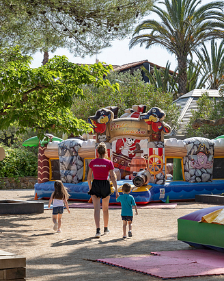 Activity Leader holding two children by the hand at the playground - Ecolodge L\'Etoile d\'Argens Campsite in Fréjus