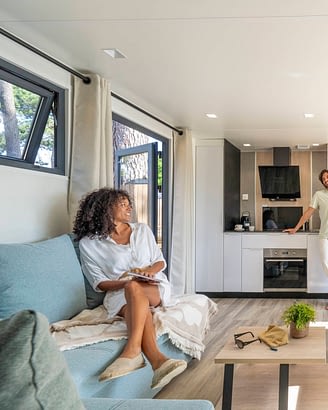 Camping Le Logis - Accommodaties - Lachend stel in de woonkamer van een premium stacaravan