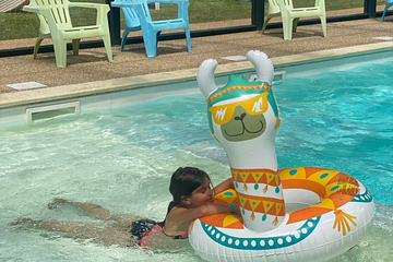 Enfant jouant avec une bou&eacute;e lama dans la piscine couverte et chauff&eacute;e du Domaine de Mesqueau, camping en Bretagne