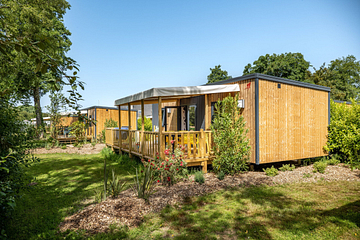 Vue sur le village des Cottages Confort Premium avec bardage bois et terrasses semi-couvertes au camping Domaine de Mesqueau.