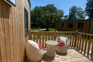 Terrasse ensoleill&eacute;e d&rsquo;un Lodge Premium avec mobilier en rotin au Domaine de Mesqueau.