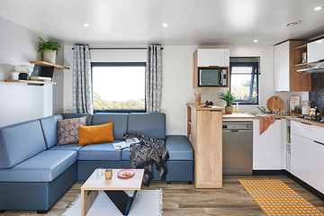 Int&eacute;rieur moderne et &eacute;l&eacute;gant d&rsquo;un Lodge Serenity Premium au Domaine de Mesqueau, avec un salon confortable et une cuisine &eacute;quip&eacute;e, incluant un lave-vaisselle.