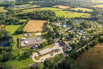 Vue a&eacute;rienne du Domaine de Mesqueau &agrave; Plougasnou, entour&eacute; de nature pr&eacute;serv&eacute;e avec des champs, des espaces verts, et des h&eacute;bergements modernes, id&eacute;al pour des vacances en pleine nature en Bretagne.