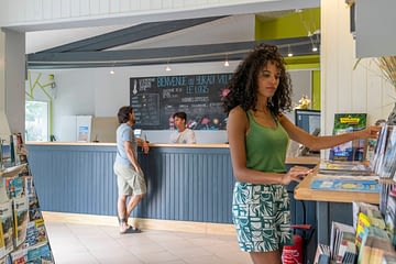 Camping Le Logis - Reception - Couple arriving at reception - Man talking to the receptionist and woman looking at the tourist information