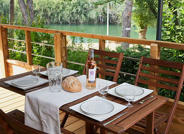 Table set with bottle of wine on the veranda of a Lodge Kabane on stilts - Ecolodge L\'Etoile d\'Argens Campsite in Fréjus