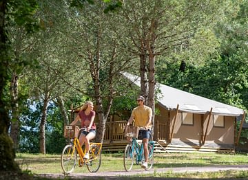Camping Les Couleurs de la Coubre - Activités et animations - Couple qui fait du vélo devant les tentes glamping