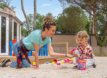 Camping Les Couleurs de la Coubre - Activités et animations - Enfant qui fait un château de sable au club enfant sous la supervision d\'une animatrice