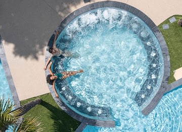 Camping Le Logis - Le Parc aquatique - Couple qui se détend sur les banquettes hydromassantes