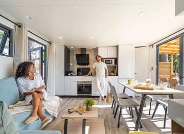 Camping Le Logis - Hébergements - Couple souriant dans le séjour d\'un mobil-home premium