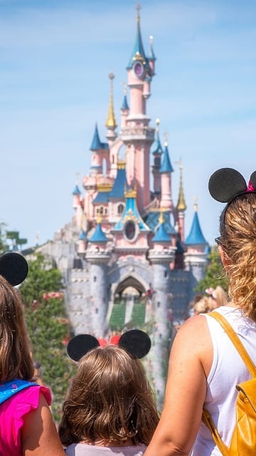 Een moeder en haar dochters kijken naar het prinsessenkasteel in Disneyland Park