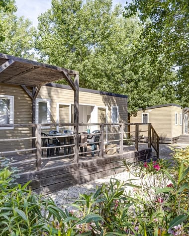 Camping Californie Plage - Les h&eacute;bergements - vue ext&eacute;rieure d\'un mobil-home entour&eacute; de v&eacute;g&eacute;tation