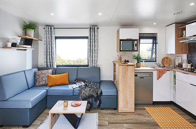 Int&eacute;rieur lumineux et moderne d&rsquo;un Lodge Premium au Domaine de Mesqueau, camping 4 &eacute;toiles en Bretagne, avec salon spacieux et cuisine &eacute;quip&eacute;e.