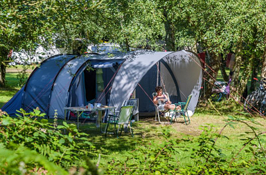 Tente familiale moderne install&eacute;e &agrave; l&rsquo;ombre au camping Mesqueau avec vacanci&egrave;re d&eacute;tendue sur chaise longue
