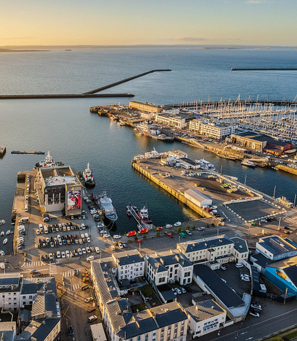Vue a&eacute;rienne du port de Brest au coucher du soleil, avec des bateaux de plaisance et des installations portuaires modernes, en Bretagne.