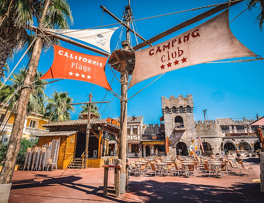 Camping Californie Plage - Galerie photo - Cœur du village avec la boutique des pirates, la terrasse du bar \"Le Black Pearl\"