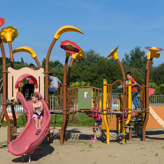 Des enfants jouant sur une aire de jeux color&eacute;e et s&eacute;curis&eacute;e au Domaine de Mesqueau, camping familial &agrave; Plougasnou, Bretagne.