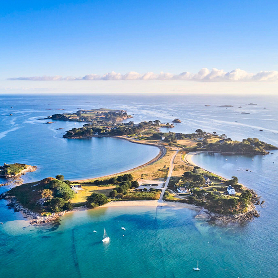 Vue aérienne de l’île Callot entourée d’eaux turquoise, accessible par un passage à marée basse près de Carantec.