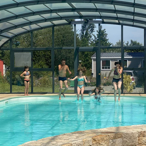 Famille s\'amusant dans la piscine couverte et chauffée du Domaine de Mesqueau, camping 4 étoiles en Bretagne.