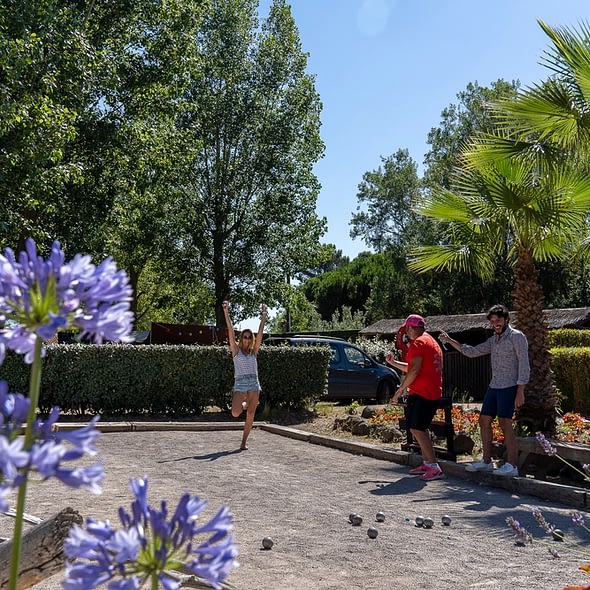 Camping Californie Plage - Galerie photo - Terrain de pétanque entouré de végétation