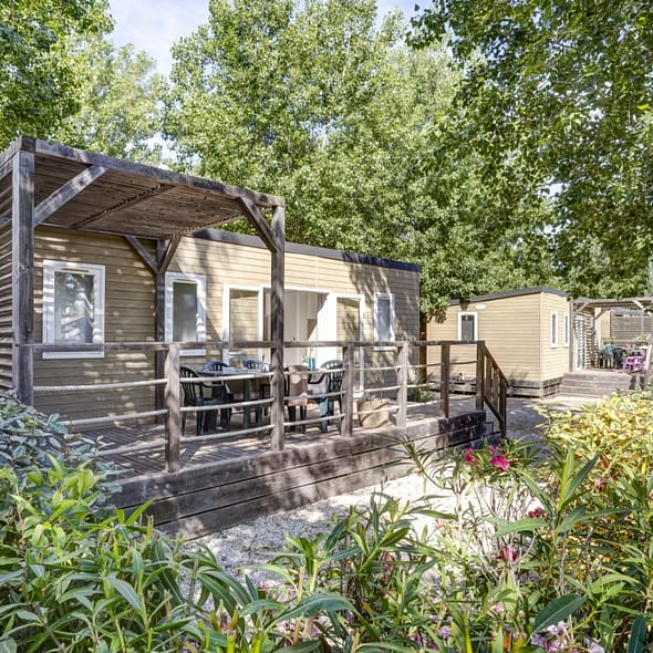 Camping Californie Plage - Les h&eacute;bergements - vue ext&eacute;rieure d\'un mobil-home entour&eacute; de v&eacute;g&eacute;tation