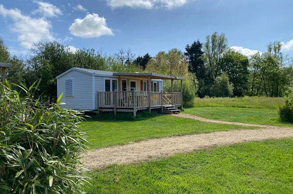 Mobil-home Simply Riviera 3 chambres pour 6 personnes au camping Domaine de Mesqueau à Plougasnou, entouré de verdure et sous un ciel bleu.