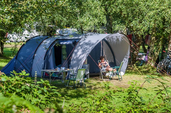 Tente familiale moderne installée à l’ombre au camping Mesqueau avec vacancière détendue sur chaise longue