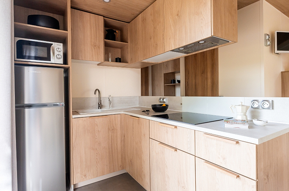 Cuisine moderne enti&egrave;rement &eacute;quip&eacute;e du Lodge &Ocirc; CONFORT avec plaques de cuisson, r&eacute;frig&eacute;rateur, micro-ondes et nombreux rangements.