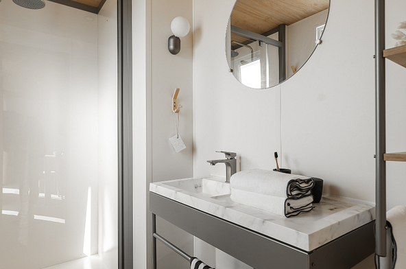 Salle de bains contemporaine du Lodge &Ocirc; CONFORT avec douche XL, meuble vasque et miroir rond.