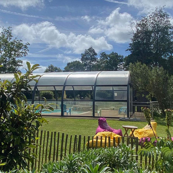  Piscine couverte du Domaine de Mesqueau, camping 4 &eacute;toiles en Bretagne, avec espace d&eacute;tente en plein air comprenant des poufs color&eacute;s.