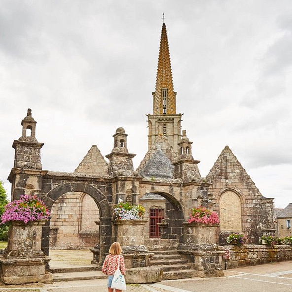 Visiteurs explorant le clo&icirc;tre de Saint-Th&eacute;gonnec, c&eacute;l&egrave;bre pour ses sculptures d&eacute;taill&eacute;es et son architecture historique en Bretagne.